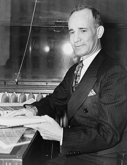 Napoleon Hill at his desk with a copy of Think and Grow Rich, 1937